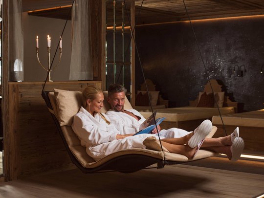 Your wellness hotel in Neustift im Stubaital awaits Couple in white robes reading together in a hanging lounge chair