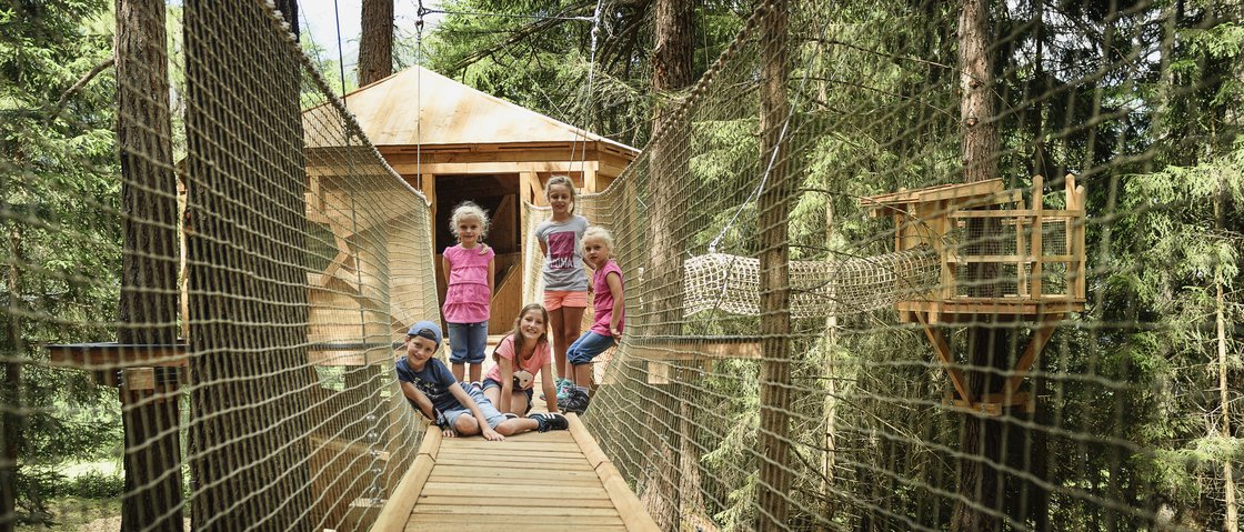 Your family hotel in Neustift im Stubaital Five children on a wooden suspension bridge in the forest with a treehouse behind