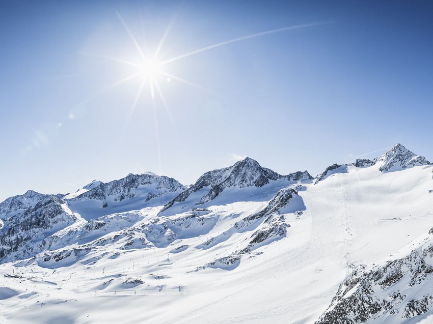 A B&B hotel at the Stubai Glacier Sunny snow-covered mountains with empty ski chairlift