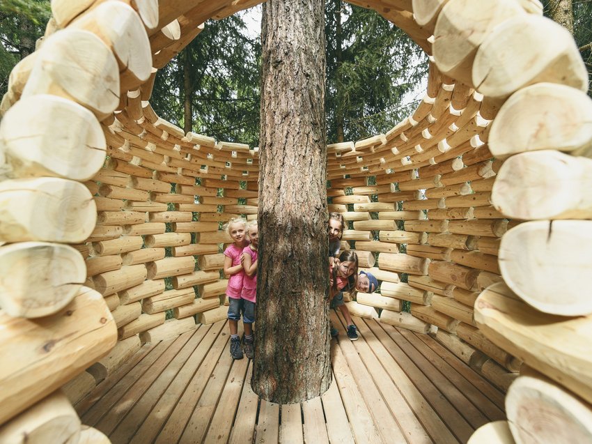 Ihr Familienhotel in Neustift im Stubaital Kinder verstecken sich hinter einem Baum in einem Holzpavillon im Wald