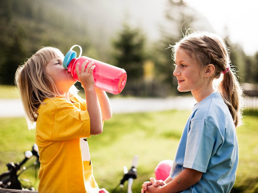 B&B Hotel mit Stubai Super Card Zwei Kinder im Freien, eines trinkt aus einer Wasserflasche, das andere schaut zu