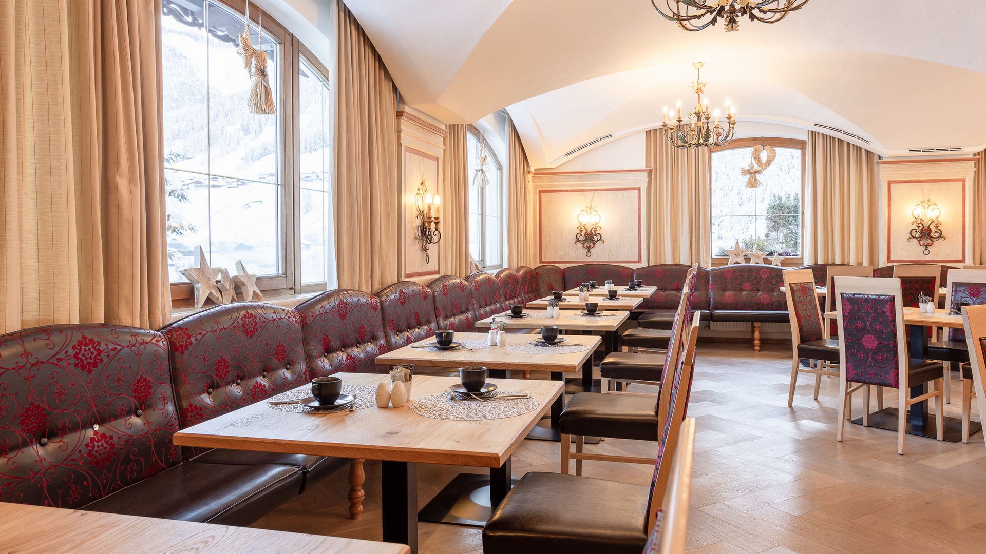 Willkommen im Hotel in Neustift im Stubaital! Elegantes Restaurant mit Holztischen, roten Sitzbänken und großen Fenstern