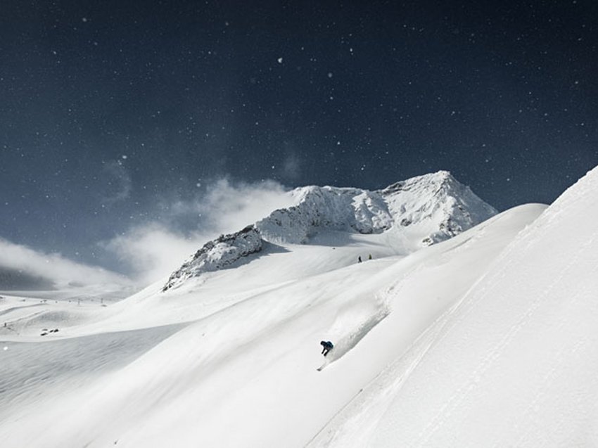 Ein B&B Hotel am Stubaier Gletscher Skifahrer fährt steilen, schneebedeckten Berghang bei bewölktem Himmel