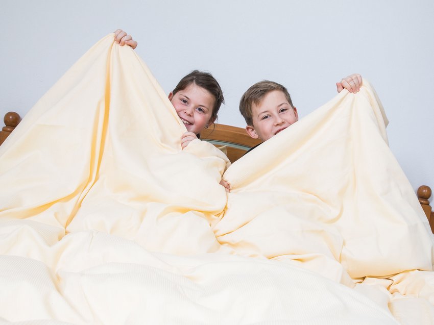 Highlights in der Unterkunft in Neustift im Stubaital Zwei lachende Kinder im Bett verstecken sich hinter einer hellen Decke