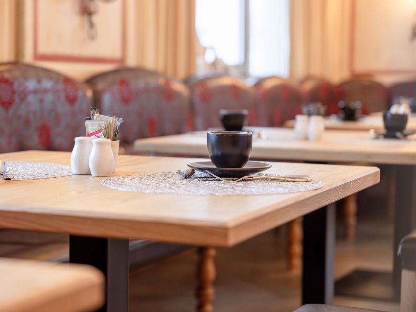 Welcome to our hotel in Neustift im Stubaital! Empty restaurant table with placemat, cup, and condiment containers
