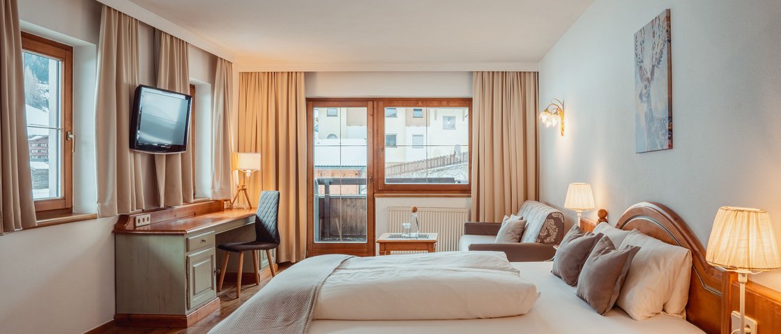 The secret to an indulgent holiday Cozy hotel room with double bed, desk, chair, and sofa near windows