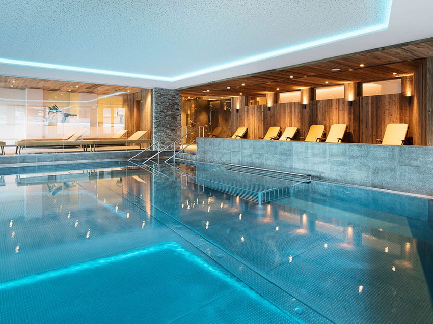 Your family hotel in Neustift im Stubaital Modern indoor pool area with lounge chairs and wooden paneling