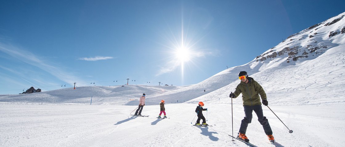 Traumtage im Skihotel im Stubaital Familie fährt Ski auf schneebedecktem Berg bei sonnigem Himmel
