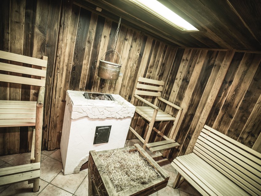 Highlights in der Unterkunft in Neustift im Stubaital Saunaraum mit Holzbänken, einem Holzofen und einem Topf an einer Kette