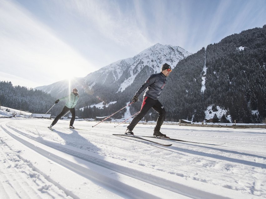 Gaudi im Winterurlaub im Stubaital Zwei Langläufer bei Sonnenschein vor schneebedeckten Bergen