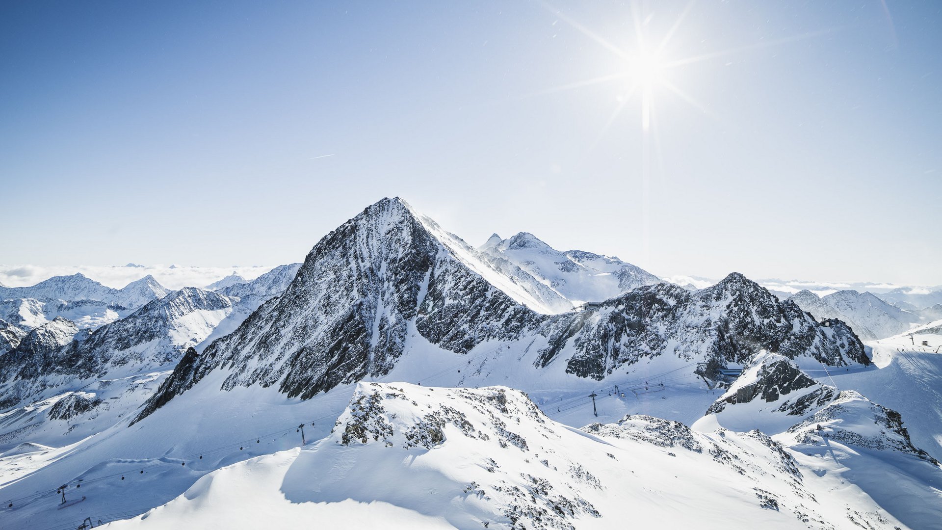A B&B hotel at the Stubai Glacier Snow-covered mountains under clear sky with bright sun
