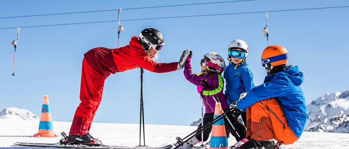 Welcome to our hotel in Neustift im Stubaital! Ski instructor giving high five to children on snowy slope
