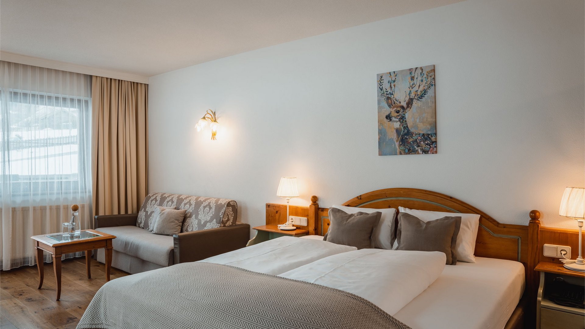 Ein B&B Hotel im Stubaital mit Halbpension-Möglichkeit Gemütliches Hotelzimmer mit Doppelbett, Sofa, Holzmöbeln und Hirschbild an der Wand