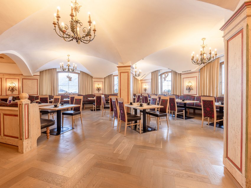 Ein B&B Hotel im Stubaital mit Halbpension-Möglichkeit Helles Restaurant mit Holzboden, Kronleuchtern und roten Stühlen