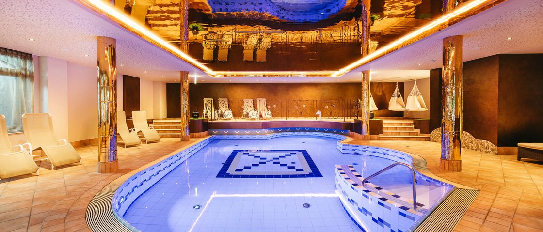 Willkommen im Hotel in Neustift im Stubaital! Moderner Innenpool mit blauen Fliesen und goldener Deckenreflexion